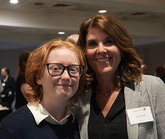 woman with dark hair and student with red hair, smiling