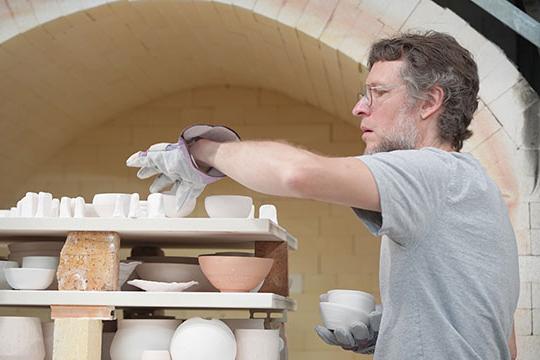 man with beard and glasses, working with ceramic art