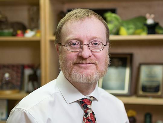 headshot of man with glasses, shirt and tie